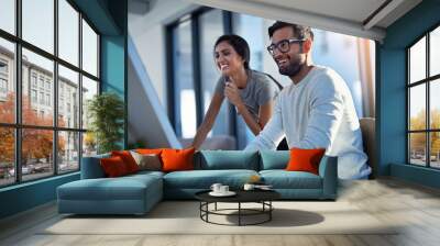 Share what makes you happy. Shot of two young coworkers using a computer together at work. Wall mural