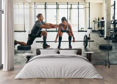 Watch your form. Shot of a fitness instructor helping a client with weight training at the gym. Wall mural