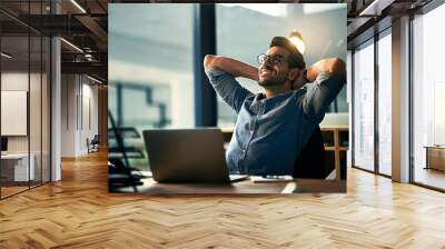 When the impossible became possible. Shot of a young businessman taking a break at his desk during a late night at work. Wall mural