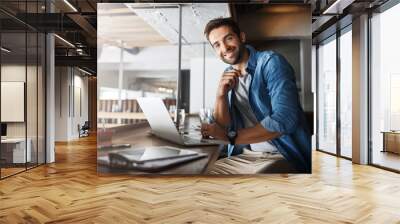 Where I come for a bit of work and leisure. a handsome young man using a laptop in a coffee shop. Wall mural