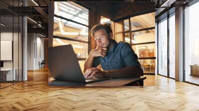 Working towards a deadline can be tricky business. Shot of a handsome young man working late in his office. Wall mural