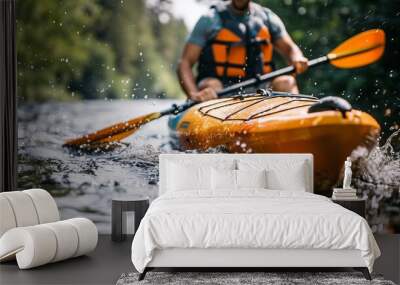 A man in a life jacket paddles an orange kayak in a river Wall mural