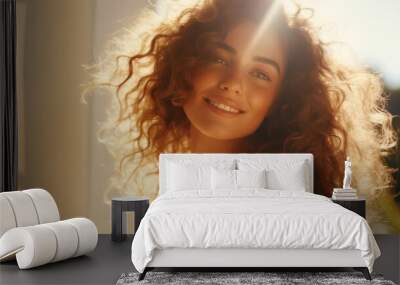 Portrait of a woman with curly hair with natural makeup in the sunlight. Happy lady enjoying the sun. Banner with copy space. Ideal for beauty or hair care advertisements. Wall mural