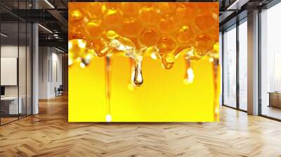 Honey dripping from honey comb on golden background. Wall mural