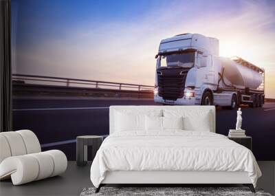 Loaded European truck tank on motorway in beautiful sunset light. On the road transportation and cargo. Wall mural