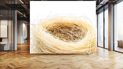 A bird's nest made of branches and blades of grass is placed on a white background. Wall mural