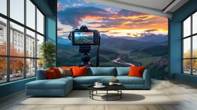 Camera capturing sunset shot. Photography using on tripod against sun rays with mountain in beautiful sundown scene. Wall mural