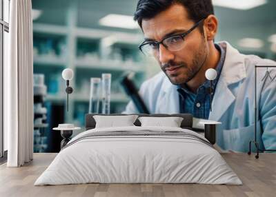 Male Chemist. Serious scientist looking at test tube in laboratory. Young man in eyeglasses holding test tube while working in chemical laboratory Wall mural