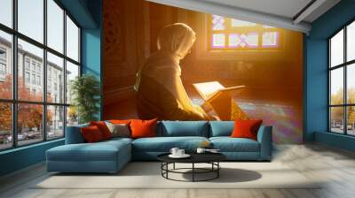 Young muslim woman reading Quran in the mosque and sunlight falling from the window Wall mural