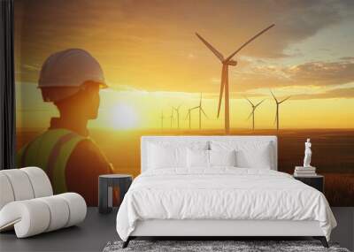 Engineer looking at wind turbines at sunset in a field Wall mural