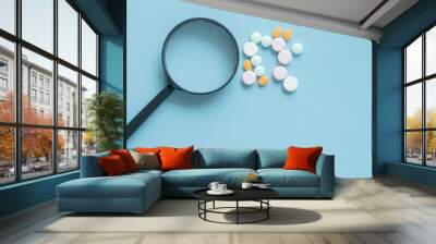 Magnifying glass with pills on blue background. pharmaceutical inspection identifies pills. Medicinal substance quality concept. Wall mural