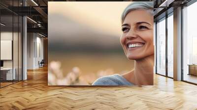 Happy woman enjoying nature with flowers in the background, glowing with happiness. Wall mural