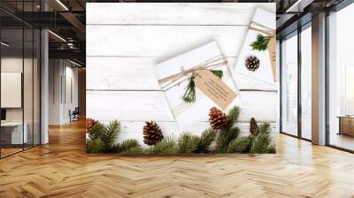 Christmas gift box with greeting tag - christmas present and pine leaves decoration on white wood table. Merry Christmas and New Year holiday background. top view. Wall mural