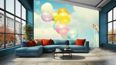 Woman hand holding colorful balloons on blue sky concept of birthday in summer and wedding honeymoon - vintage color effect Wall mural