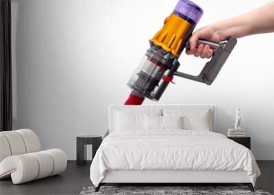 Woman's hand holds Modern cordless vacuum cleaner isolated on white background. New technologies. Wall mural