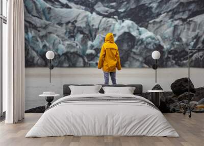 Beautiful girl in a yellow raincoat admires the powerful big Katla glacier during rainy weather in southern Iceland Wall mural