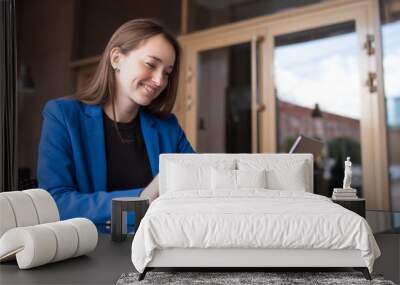 Business woman with laptop sits at the table and smiles Wall mural