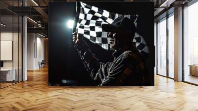 The checkered flag of the Formula 1 flagship flutters before the night race under the illumination of floodlights and headlights. Perfect for motorsport promotions and race event advertisements Wall mural