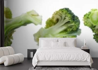 Multiple broccoli florets arranged in a line, showcasing various sizes and angles, isolated on a white background. Wall mural