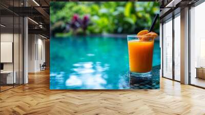 A glass of orange juice by the pool. Wall mural