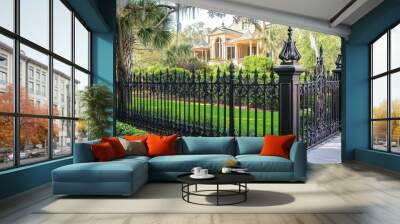 Ornate black iron fence encloses lush greenery. Wall mural