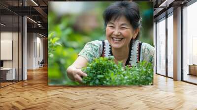 Smiling woman holding green plants. Wall mural