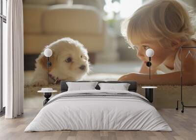 Adorable blonde toddler girl lying on carpet face-to-face with fluffy white puppy in sunlit living room, copy space Wall mural