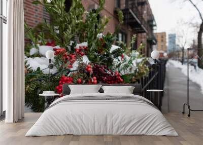 Outdoor Christmas Holiday Pine Branches and Pine Cones with Red Berry and Light Decorations Covered with Snow Outside a Residential Building in New York City along a Sidewalk Wall mural