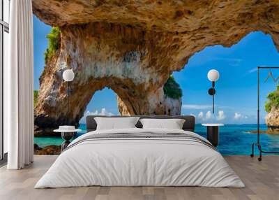 Natural stone arch framing a view of a tropical paradise. Wall mural