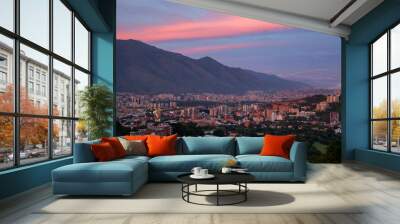 The setting sun paints the clouds above the mountains and buildings of Caracas, Venezuela. Wall mural