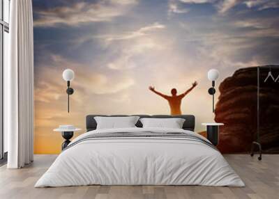 a person reaching up from a high point, set against a sunset. expressing freedom Wall mural