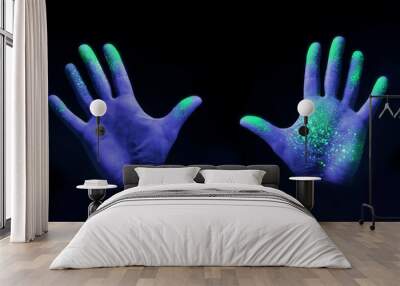 Human hands glowing from UV ultra violet light showing bacteria and viruses on a black background, showing the importance of hand washing. Wall mural