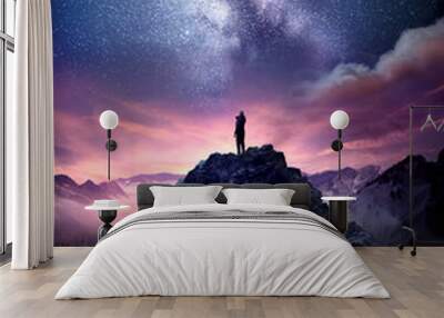 Night sky long exposure landscape. A man standing on a high rock watching the stars rise into the night sky. Photo composite. Wall mural