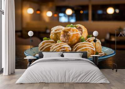 Close-up of a plate of Japanese Takoyaki topped with green onions and sauce in a cozy Japanese restaurant setting with soft lighting and traditional interior design.  Wall mural