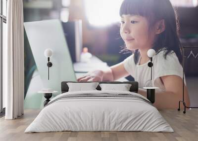 Little asian girl  using laptop to studying . selected focus on eye with blurred background . Wall mural