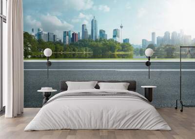 Side view of asphalt road highway with lake garden and modern city skyline in background. Wall mural