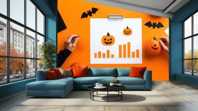 Creative workspace featuring Halloween-themed pumpkins and graphs on an orange background, perfect for festive marketing. Wall mural