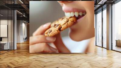 Close-up of a woman eating a chocolate chip cookie. Wall mural