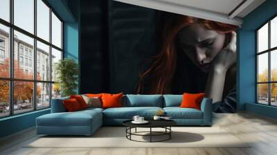 Portrait of a young redhead woman sitting on a floor, hopeless and depressed against a textured, cracked wall. Wall mural