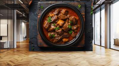 Top view of savory beef stew in a bowl, a classic comfort food on a dark surface. Wall mural