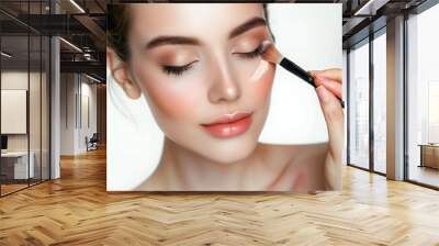 Beautiful woman applying professional make-up with face brush, model face detail with cosmetic make up in process Wall mural