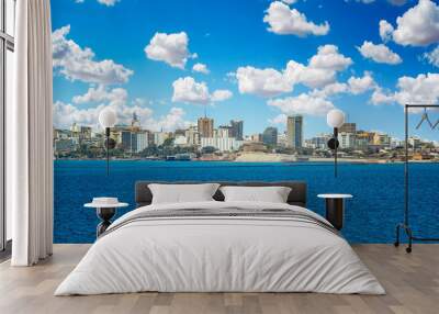 View of the Senegal capital of Dakar, Africa. It is a city panorama taken from a boat. There are large modern buildings and a blue sky with clouds. Wall mural