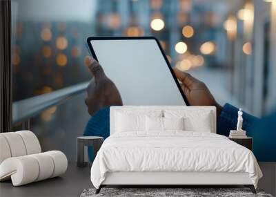 hands in sleek blue suit jacket holding black tablet iPad Pro mockup vertical with white blank screen, with a modern rooftop bar and city lights  background Wall mural