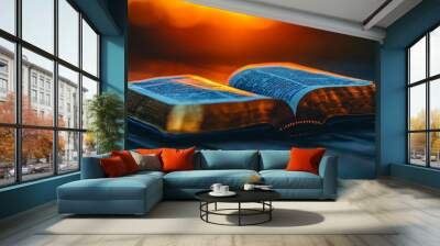 A golden-edged book open to a page filled with words, rests on a wooden surface bathed in the warm light of the setting sun. Wall mural