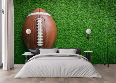 American football ball on vibrant green grass field background. Top view, American football, ball, grass field, green Wall mural