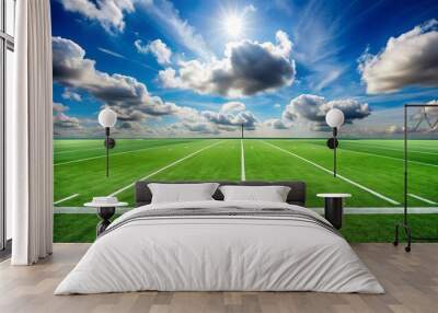 Green football field under blue sky background with fluffy white clouds Wall mural