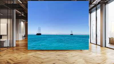 Two masted ships near coral reefs in the Red Sea. Tourist walks by the sea on a sunny day Wall mural