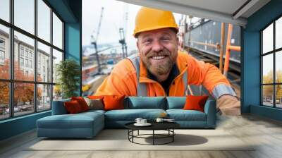 A friendly construction worker in an orange hard hat smiles at the camera while on-site, showcasing a positive work environment on a sunny day at a building project. Wall mural