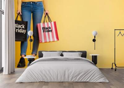 A person holding two Black Friday shopping bags against a bright pink background, emphasizing the excitement of holiday shopping deals. Wall mural