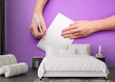 A woman's hand holds a notebook with white sheets on a light background. A place for text, a view from above. Wall mural